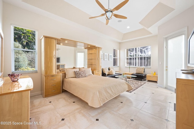 bedroom featuring a tray ceiling, recessed lighting, a ceiling fan, light tile patterned flooring, and baseboards