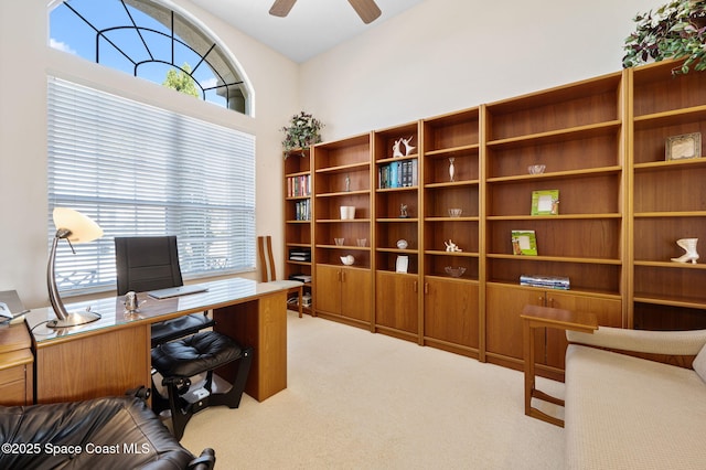 carpeted office space with plenty of natural light and a ceiling fan