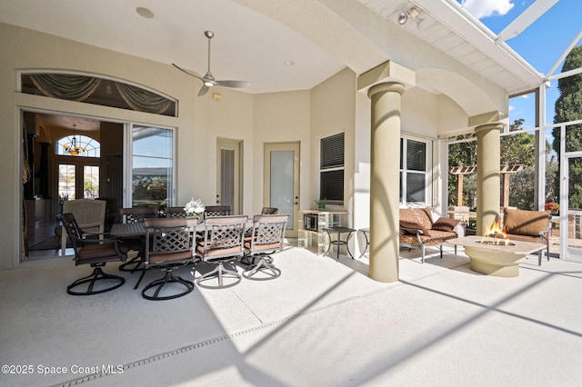 view of patio / terrace with ceiling fan, glass enclosure, an outdoor fire pit, and outdoor dining area