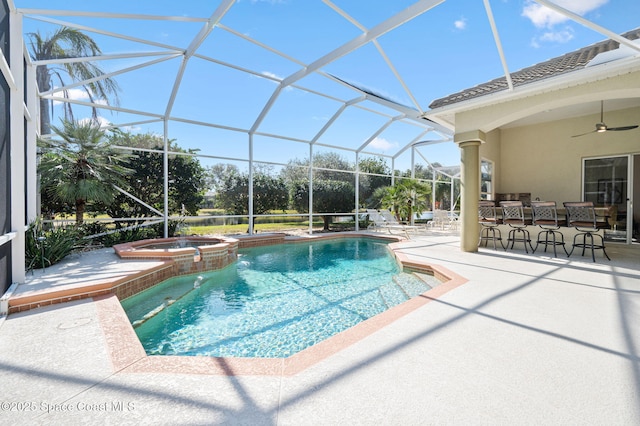 view of swimming pool with a ceiling fan, glass enclosure, outdoor dry bar, a patio area, and a pool with connected hot tub