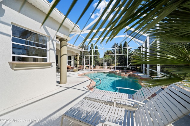 view of pool with a lanai, a pool with connected hot tub, and a patio