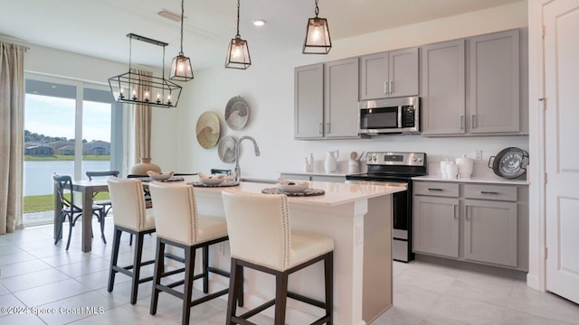 kitchen featuring decorative light fixtures, gray cabinets, a water view, and appliances with stainless steel finishes