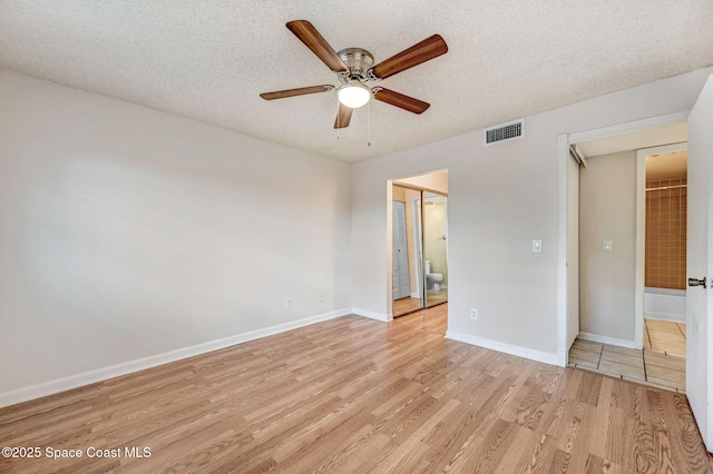 unfurnished bedroom with ceiling fan, a textured ceiling, light wood-type flooring, and ensuite bath