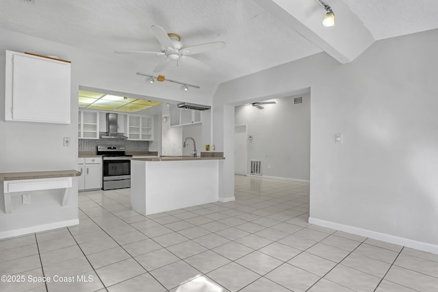 kitchen with stainless steel electric range oven, white cabinets, decorative backsplash, ceiling fan, and wall chimney exhaust hood