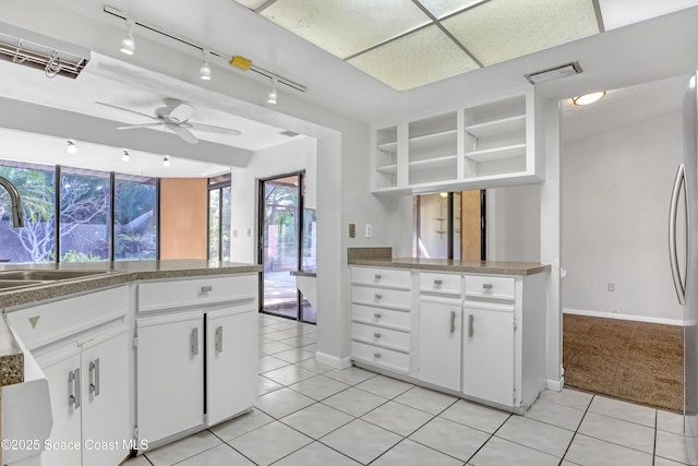 kitchen with sink, light tile patterned floors, kitchen peninsula, and white cabinets