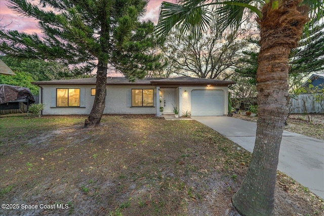 view of front of home with concrete driveway, an attached garage, and stucco siding