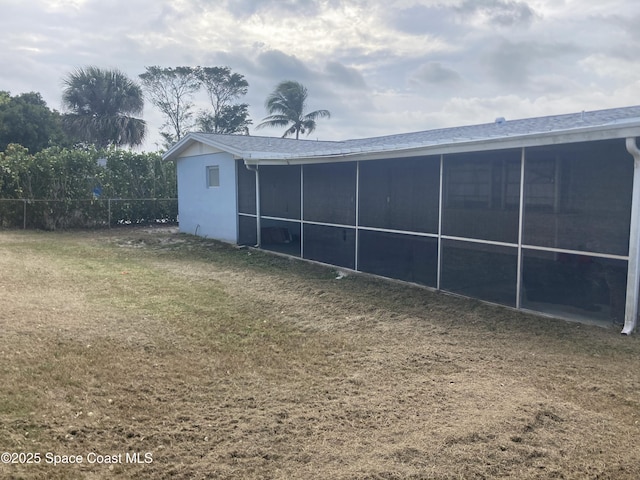 rear view of property featuring fence, a lawn, and a sunroom