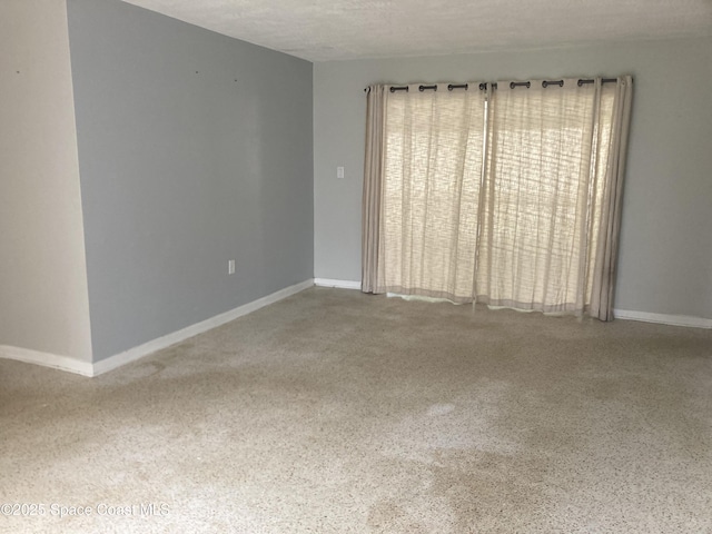 spare room featuring a wealth of natural light, a textured ceiling, speckled floor, and baseboards