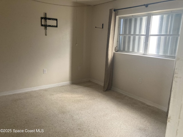 empty room with baseboards and speckled floor