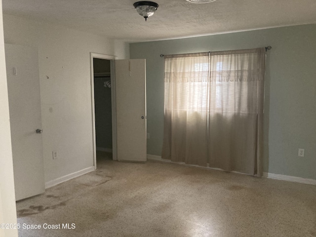 spare room featuring a textured ceiling and baseboards