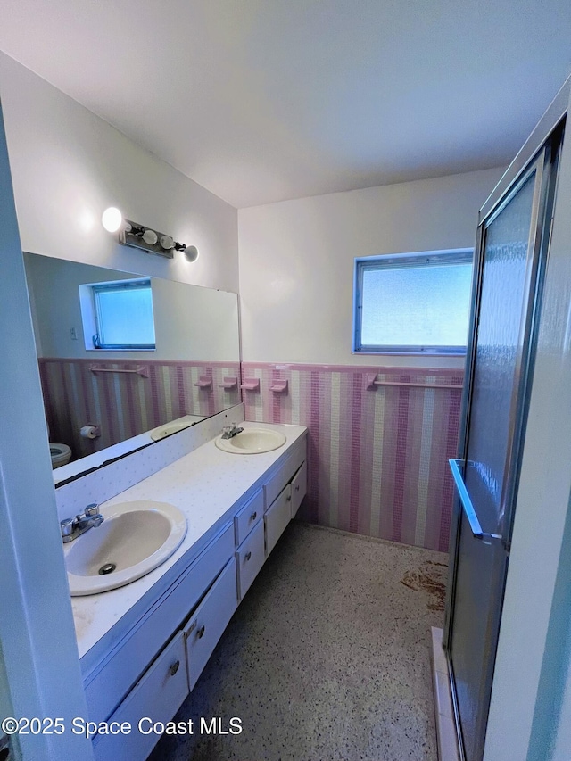 full bathroom with a stall shower, a sink, and wainscoting
