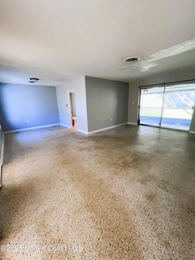 unfurnished living room featuring speckled floor, baseboards, and visible vents