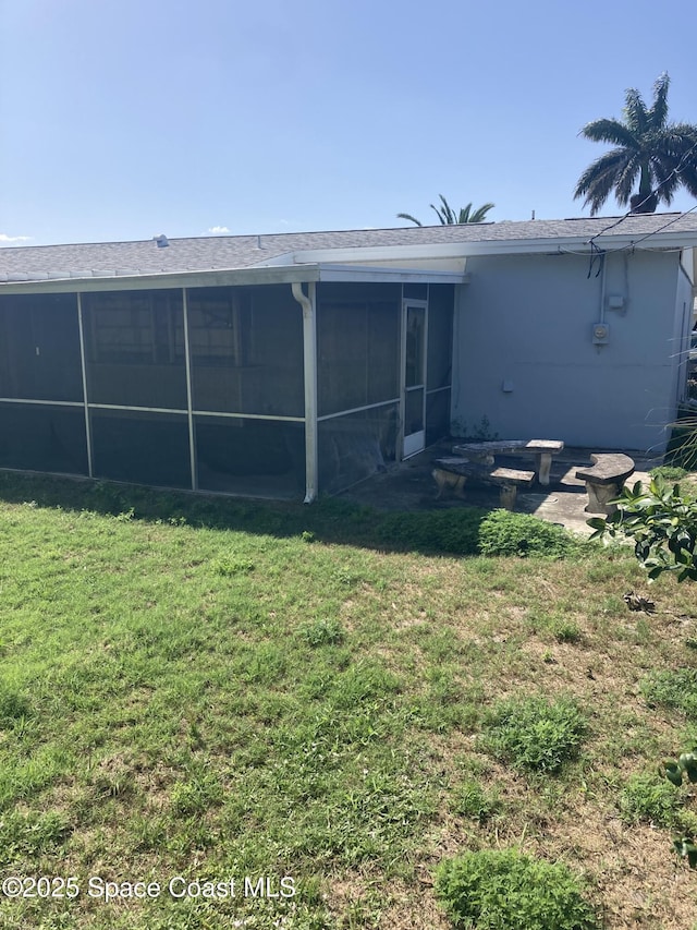 rear view of house with a sunroom, a lawn, and stucco siding