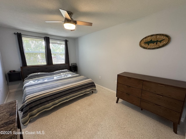 carpeted bedroom featuring ceiling fan and a textured ceiling