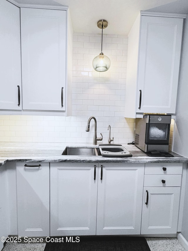 kitchen with pendant lighting, sink, white cabinetry, and tasteful backsplash
