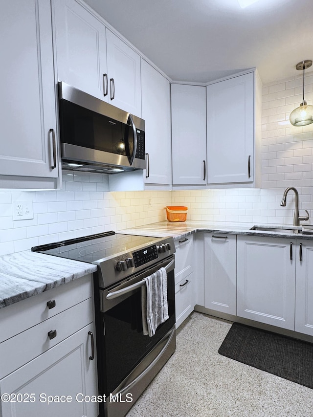 kitchen with white cabinetry, stainless steel appliances, sink, and light stone counters
