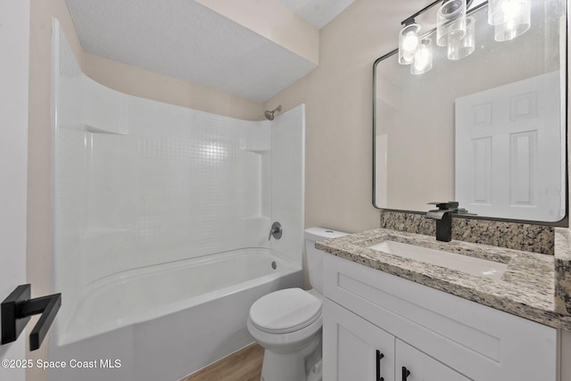 full bathroom featuring vanity, wood-type flooring, a textured ceiling, shower / washtub combination, and toilet