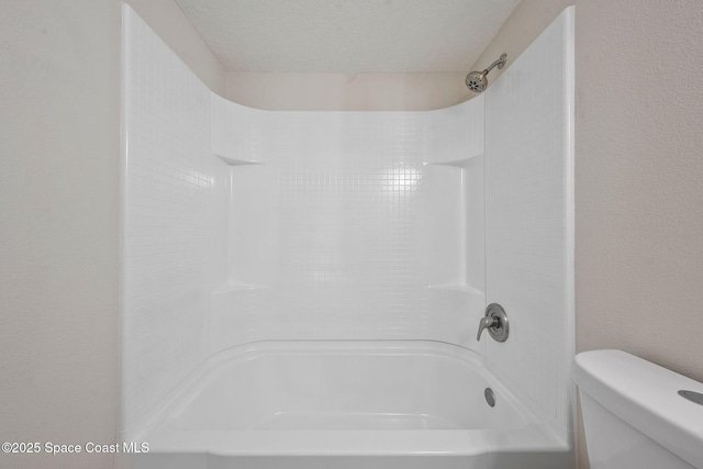 bathroom with a textured ceiling, tub / shower combination, and toilet