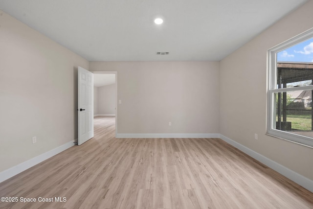 spare room with plenty of natural light and light hardwood / wood-style flooring