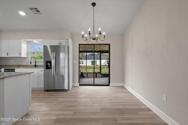 kitchen featuring a chandelier, stainless steel fridge with ice dispenser, hanging light fixtures, light stone countertops, and white cabinets