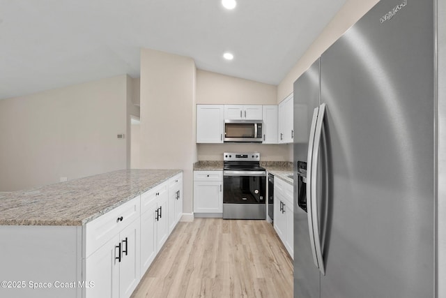 kitchen with lofted ceiling, white cabinets, stainless steel appliances, light stone countertops, and light hardwood / wood-style flooring