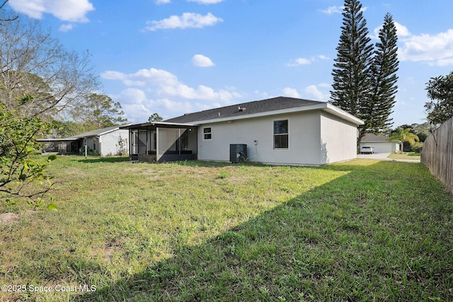 rear view of property featuring a sunroom, central AC unit, and a lawn