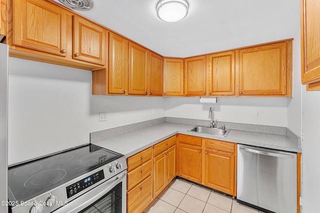 kitchen featuring light tile patterned floors, stainless steel appliances, light countertops, brown cabinetry, and a sink