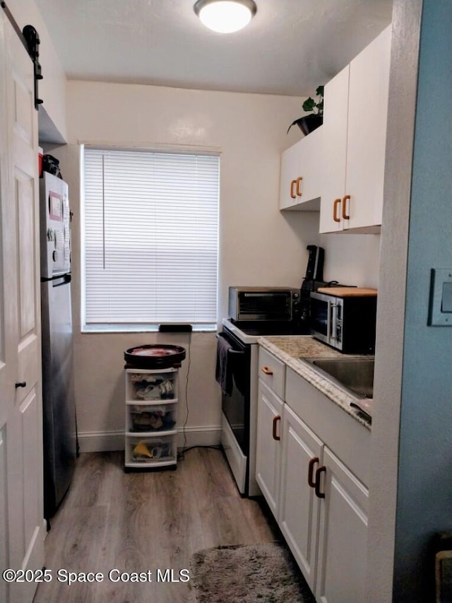 kitchen featuring white cabinetry, stainless steel appliances, a barn door, and dark hardwood / wood-style floors