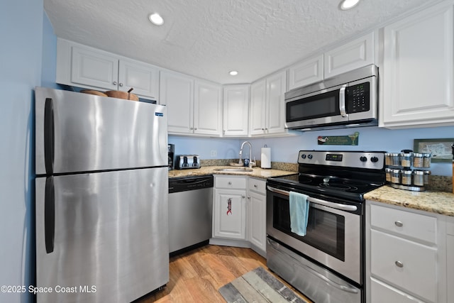 8600 Ridgewood Ave Unit 1308, Cape Canaveral, FL 32920 - kitchen featuring appliances with stainless steel finishes, white cabinets, light wood finished floors, a textured ceiling, and recessed lighting
