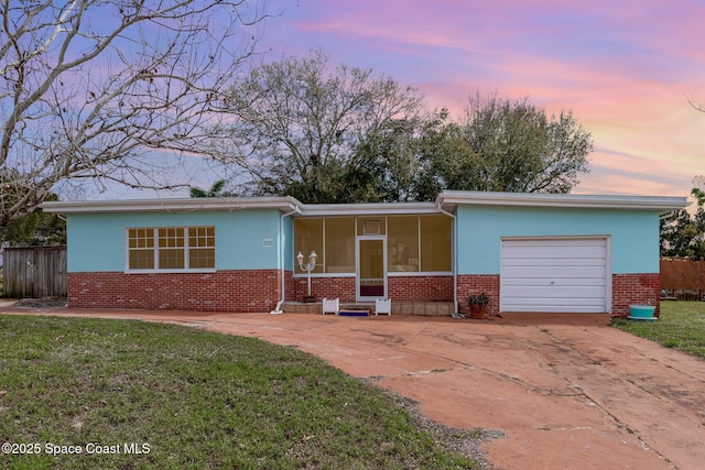 ranch-style home featuring a garage, brick siding, a sunroom, driveway, and a front lawn