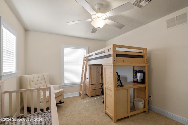 bedroom with ceiling fan, light colored carpet, and a textured ceiling