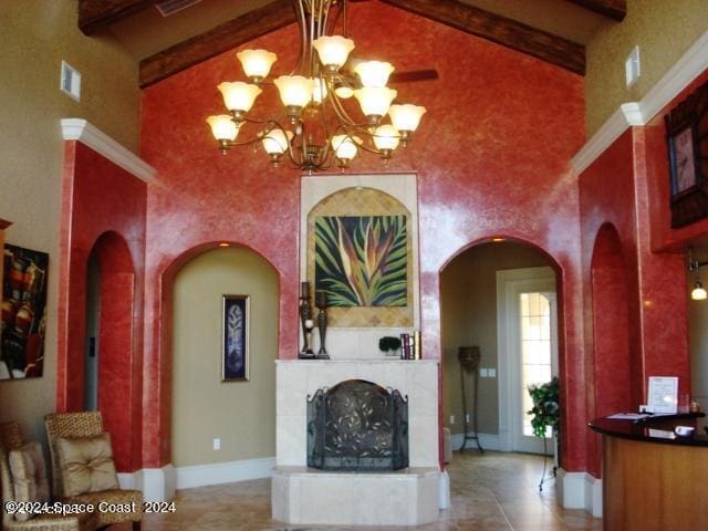 interior space with beam ceiling, a tile fireplace, a chandelier, and a high ceiling