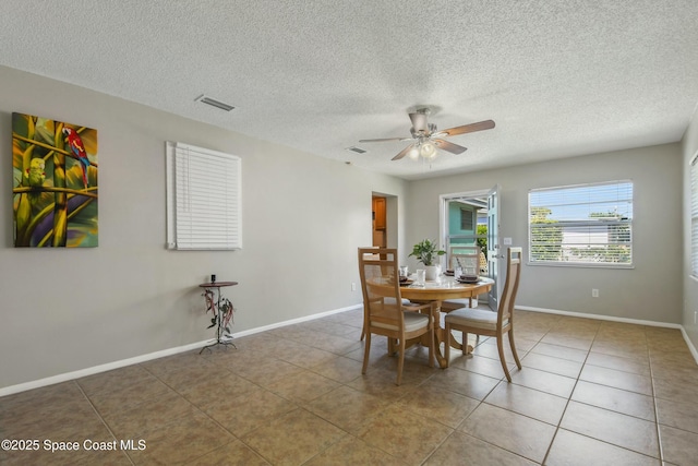 tiled dining area with a textured ceiling and ceiling fan