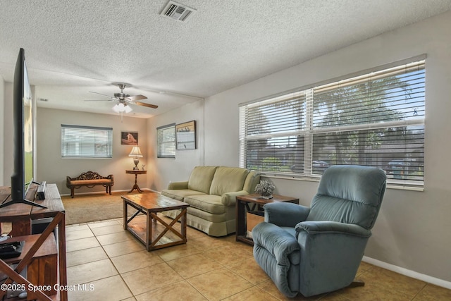 living room featuring ceiling fan, light tile patterned floors, and a textured ceiling