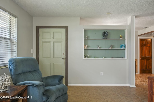 living area with tile patterned floors, built in features, and a textured ceiling