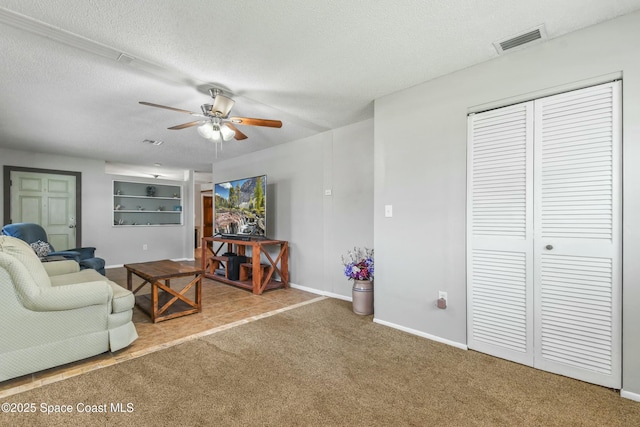 living room with ceiling fan, carpet floors, and a textured ceiling