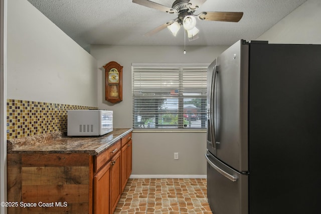 kitchen with stainless steel refrigerator, ceiling fan, tasteful backsplash, and a textured ceiling