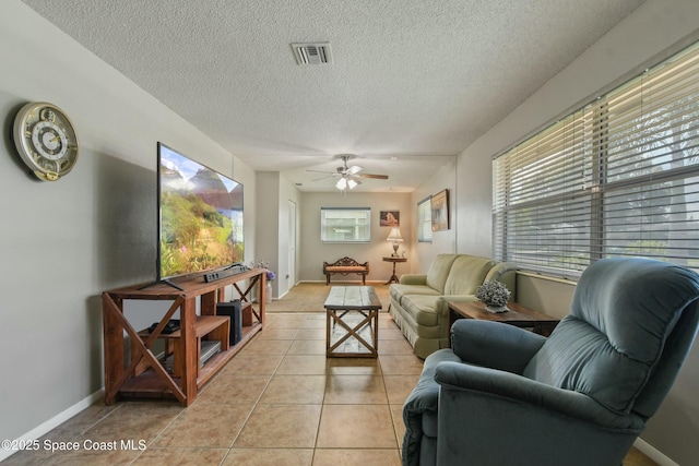 tiled living room with ceiling fan and a textured ceiling