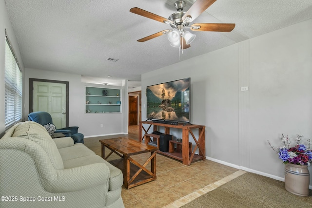 tiled living room with ceiling fan and a textured ceiling