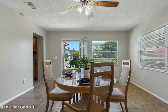 tiled dining room with a textured ceiling and ceiling fan