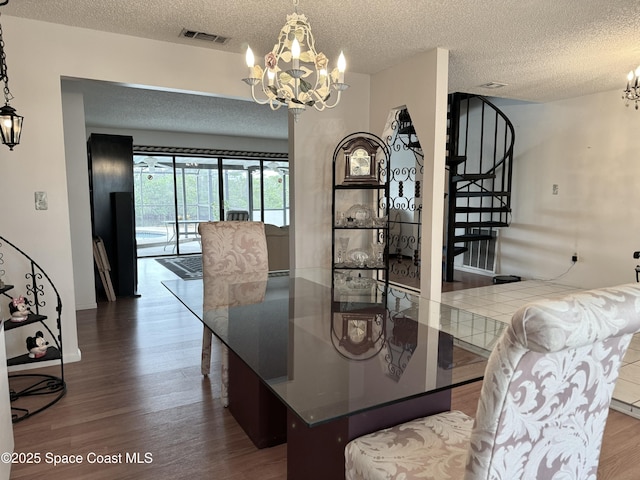 dining room featuring wood-type flooring, a notable chandelier, and a textured ceiling