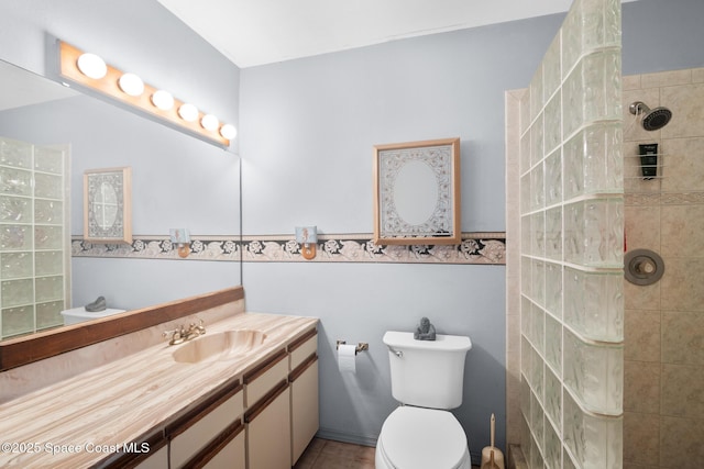 bathroom with vanity, a tile shower, and toilet