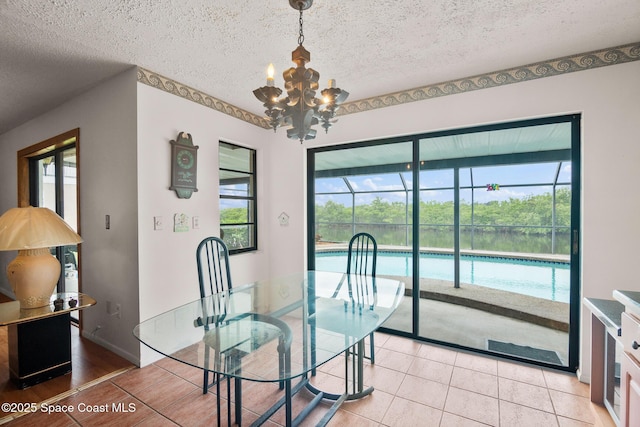 tiled dining space with a chandelier and a textured ceiling