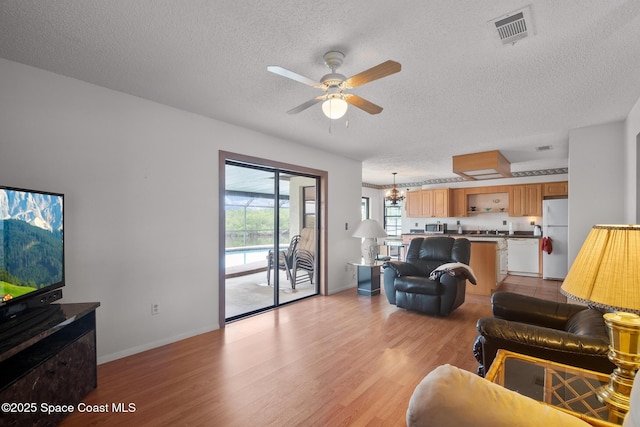 living room with ceiling fan, light hardwood / wood-style floors, and a textured ceiling