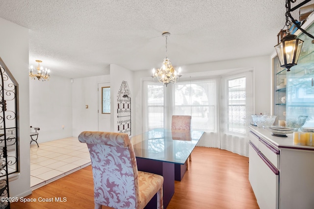 dining area featuring a textured ceiling, a chandelier, and light hardwood / wood-style floors