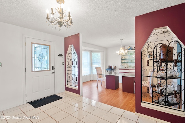 foyer with light tile patterned floors, a notable chandelier, and a textured ceiling