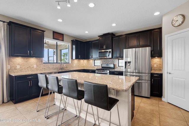 kitchen featuring a breakfast bar, a kitchen island, stainless steel appliances, and a sink