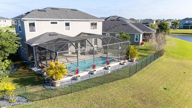 rear view of property with glass enclosure, a lawn, a fenced backyard, and a fenced in pool