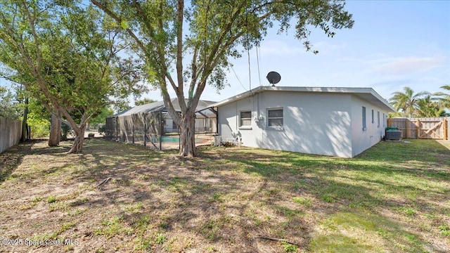 rear view of property with a fenced in pool, a lanai, a fenced backyard, and a yard