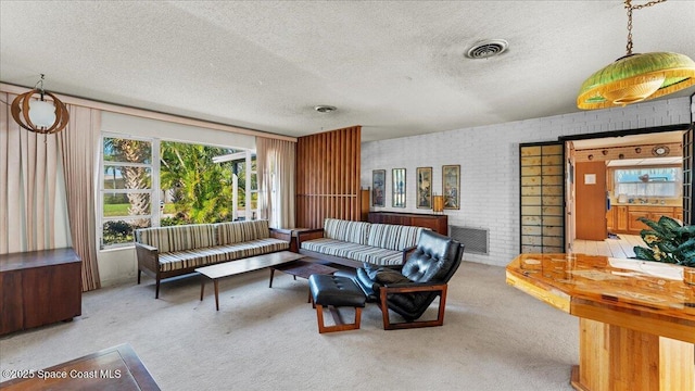 carpeted living room with brick wall, visible vents, and a textured ceiling